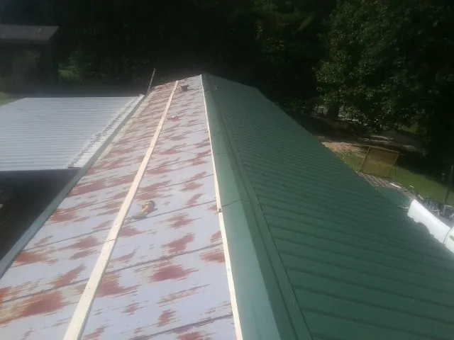 Old rusted panels beside newly installed green metal roofing — Wind Damage Roof Repair by Roofing Brothers in Reidville