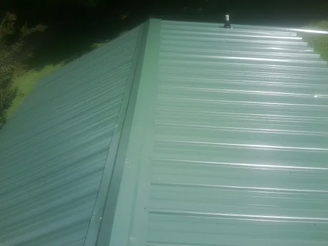 New green metal panels meeting at the ridge of a roof — Flat Roof Repair work by our crew in Reidville