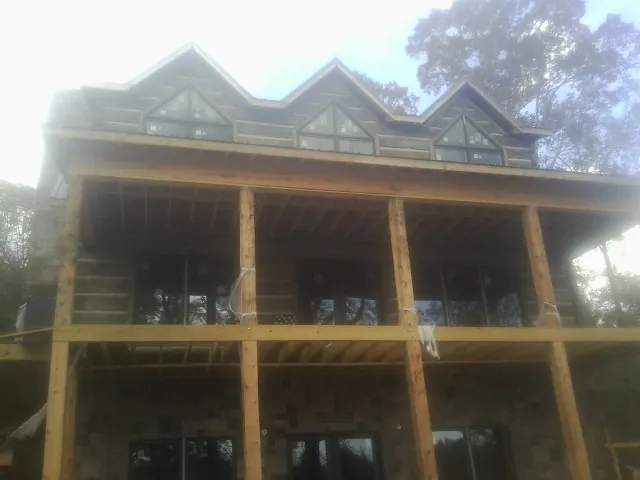 Dormers and porch framing on a large log home under construction — Roof Coating work by our crew in Reidville