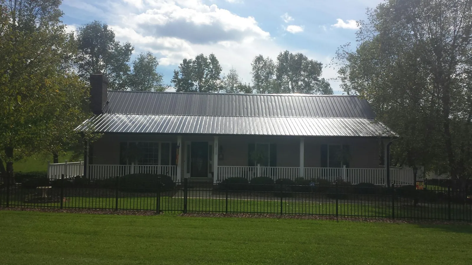 Gray metal roof on a brick ranch with a full width front porch — Gutter Guard Installation work by our crew in Reidville