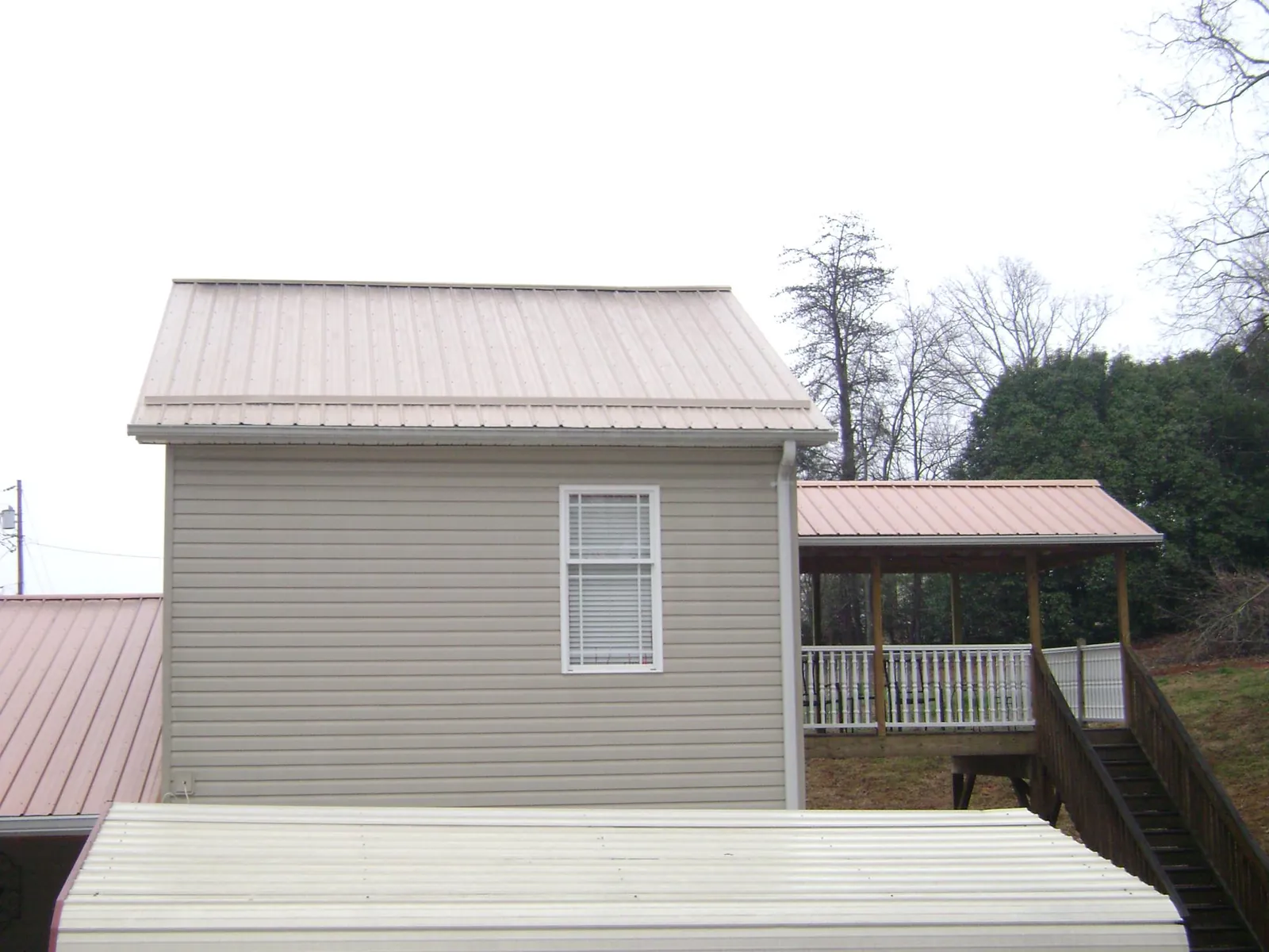 Tan metal roofs on a two story addition and attached porch, from a Roof Replacement job in Reidville