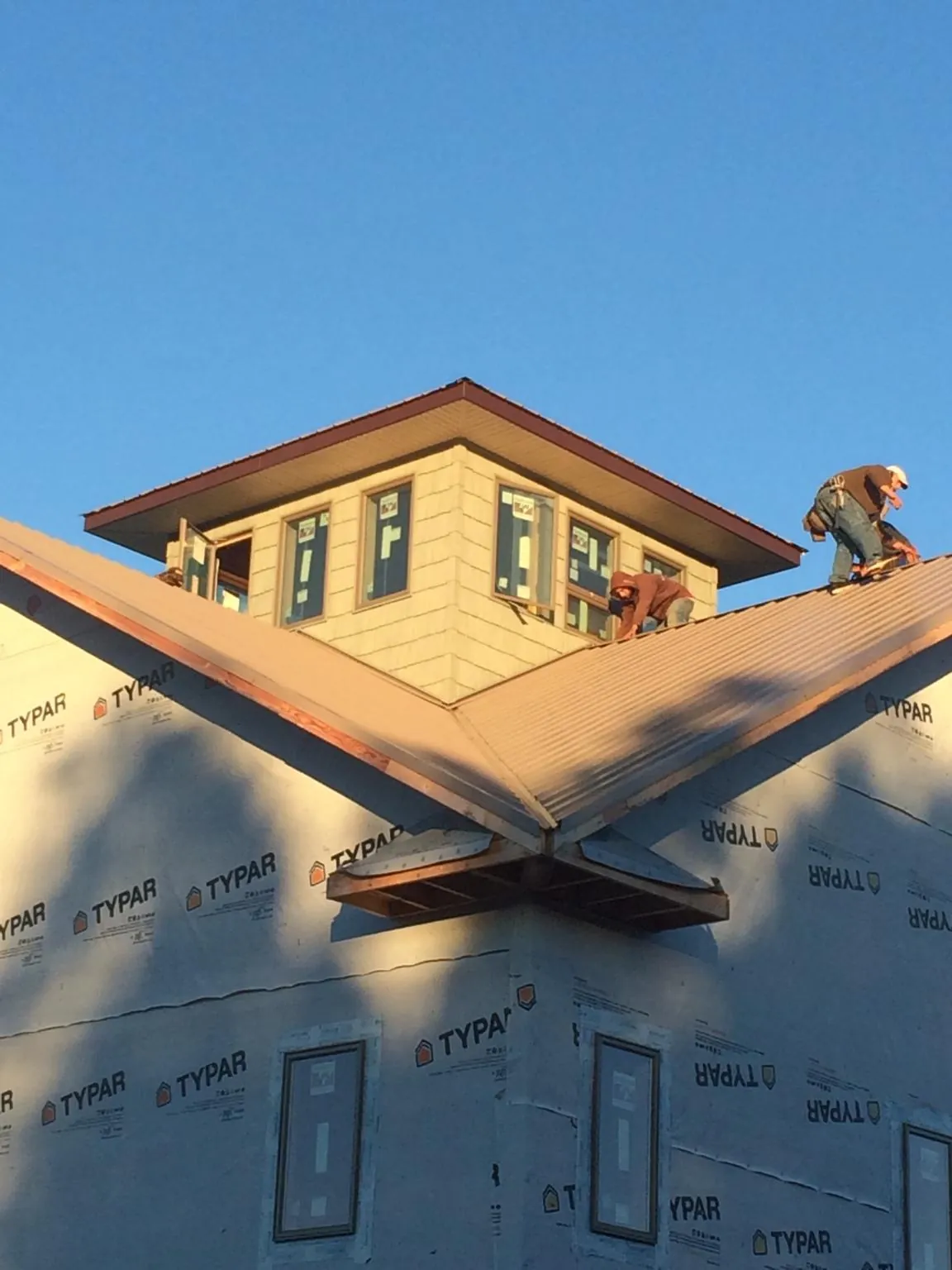 Roofers working around a rooftop cupola on a new metal roof at sunset — Roof Waterproofing in Reidville by Roofing Brothers